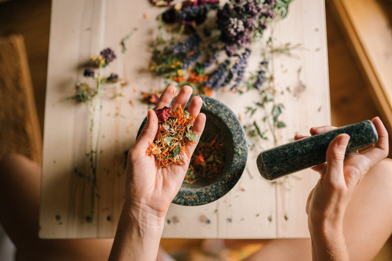 Hands preparing herbal medicine with mortar and pestle for holistic healing