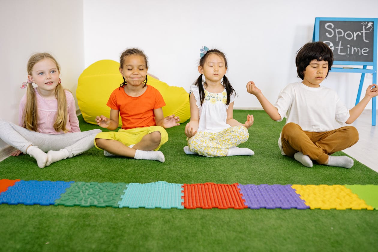 Diverse group of children meditating together in a classroom yoga session, practicing mindfulness as a group