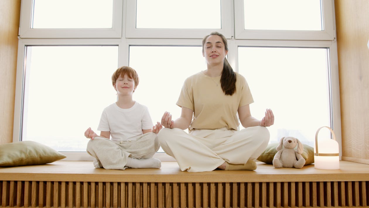Mother and son practicing yoga and meditation together at home, demonstrating family mindfulness bonding