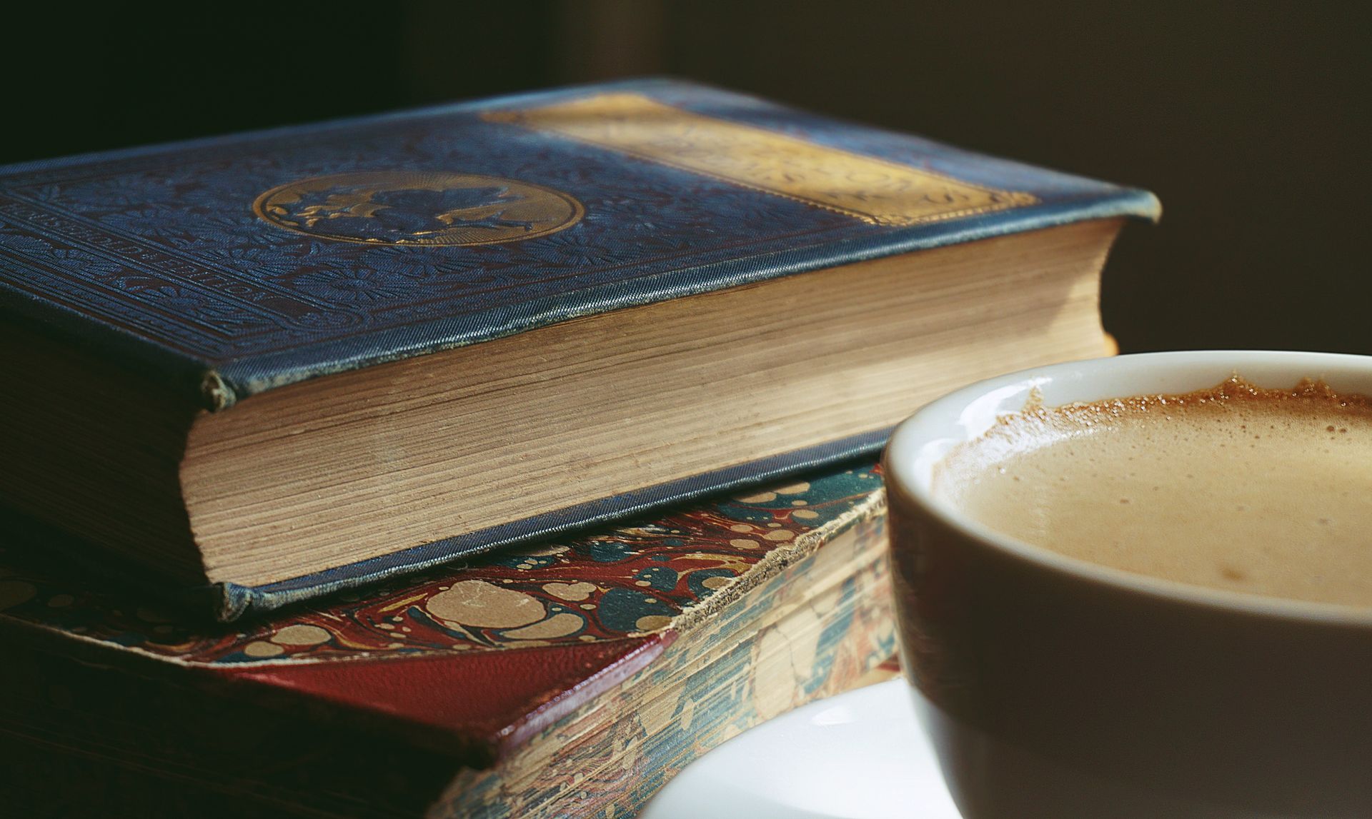 Stack of vintage books with a cup of coffee on a warm wooden surface