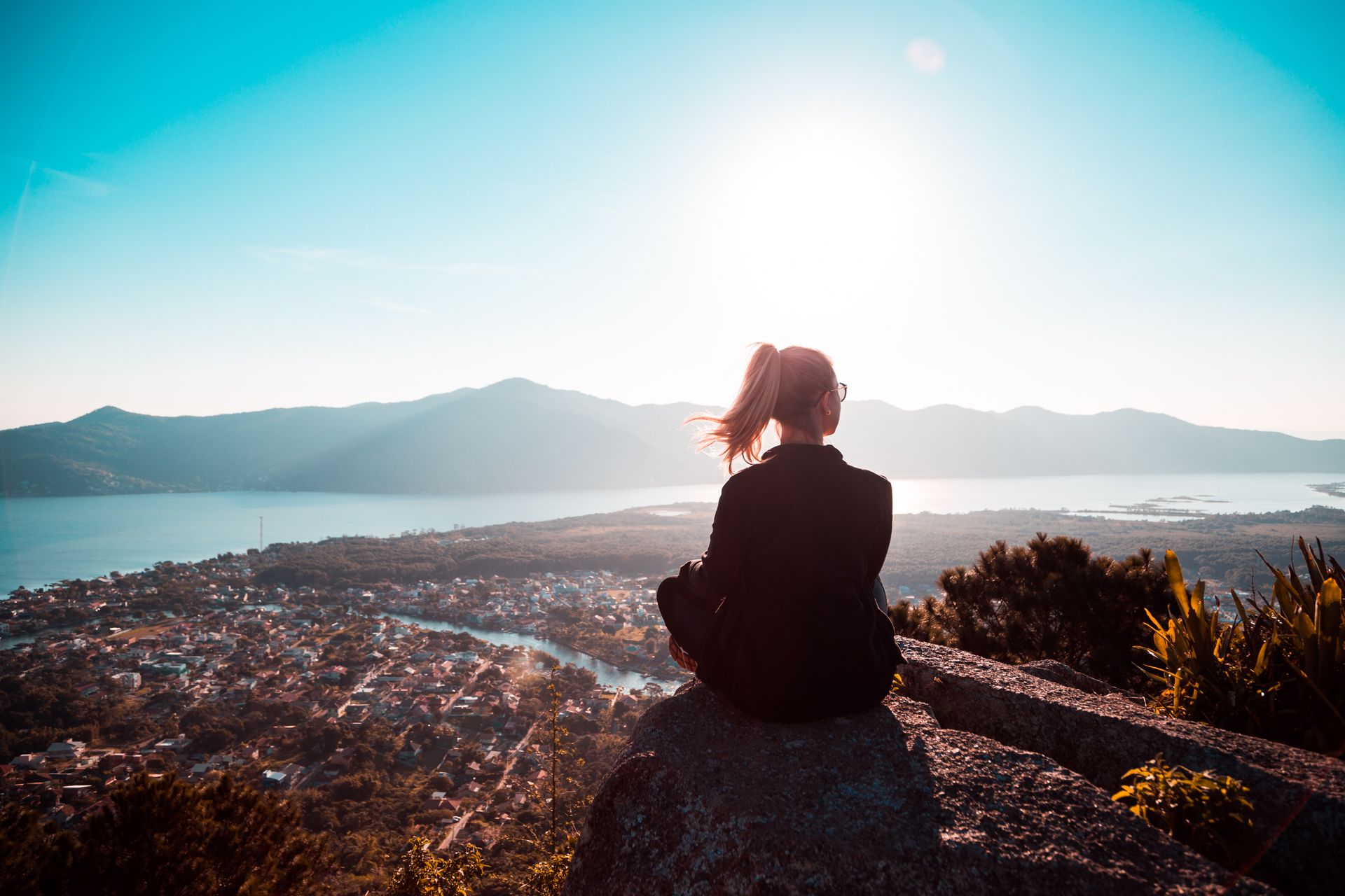 Woman sitting peacefully on a rock overlooking a golden-hour mountain vista